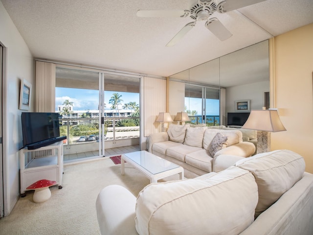 living room featuring ceiling fan, a wall of windows, carpet floors, and a textured ceiling