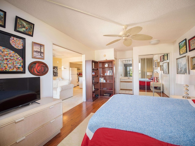 bedroom featuring ensuite bathroom, a textured ceiling, ceiling fan, wood-type flooring, and white fridge