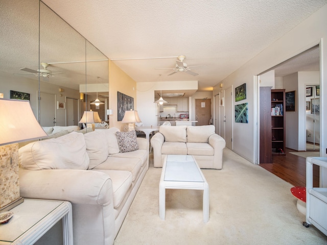 living room with ceiling fan, light colored carpet, and a textured ceiling