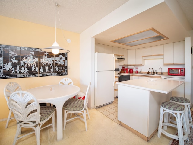 kitchen with white appliances, light colored carpet, sink, decorative light fixtures, and white cabinets