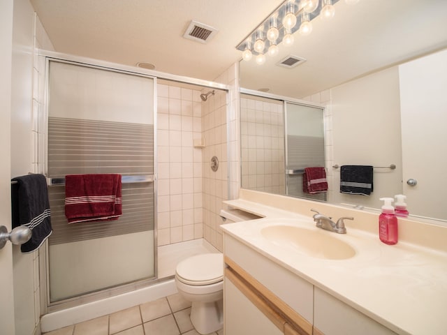 bathroom featuring tile patterned floors, vanity, a shower with shower door, and toilet