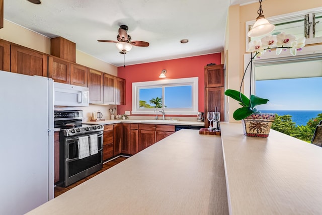 kitchen with white appliances, light countertops, hanging light fixtures, and a sink