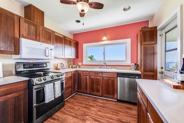 kitchen with dark wood-style floors, light countertops, appliances with stainless steel finishes, a sink, and ceiling fan