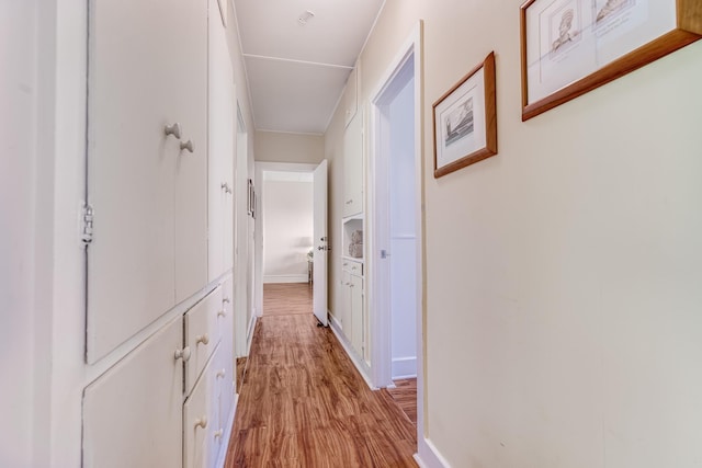 hallway with light wood finished floors and baseboards