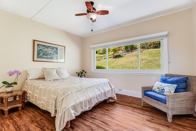 bedroom with a ceiling fan, baseboards, and wood finished floors