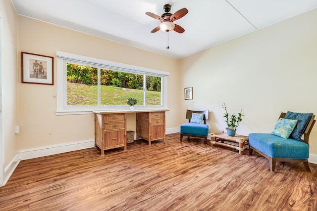 living area with light wood-type flooring, ceiling fan, and baseboards