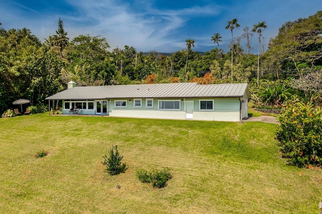 view of front of home with a standing seam roof, metal roof, and a front yard