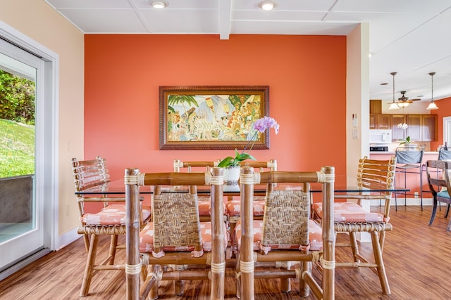 dining area with beam ceiling, baseboards, and light wood finished floors