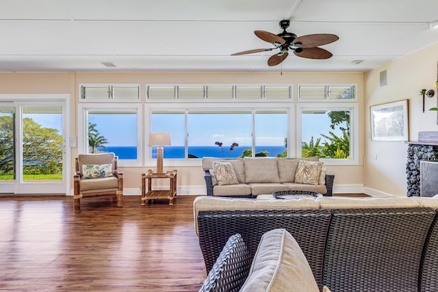 sunroom / solarium with ceiling fan, a premium fireplace, a water view, and visible vents