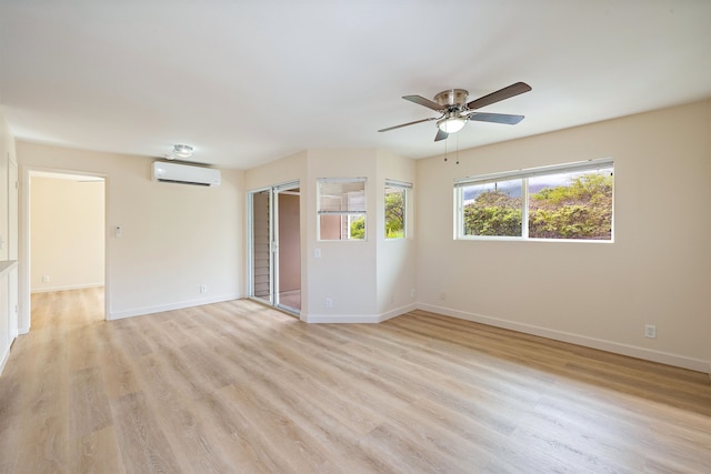 empty room featuring a wall mounted AC, light wood-type flooring, and ceiling fan