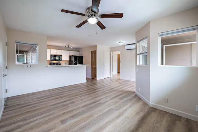 unfurnished living room featuring light hardwood / wood-style floors, a wall mounted AC, and ceiling fan