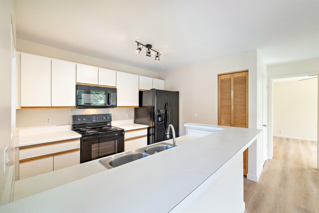 kitchen featuring black appliances, sink, rail lighting, white cabinets, and light hardwood / wood-style flooring