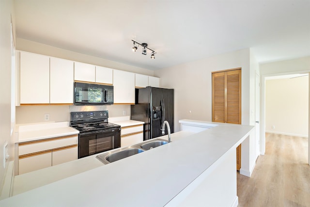 74 Kunihi Ln Unit 430, Kahului, HI 96732 - kitchen with black appliances, light wood-type flooring, white cabinets, light countertops, and a sink