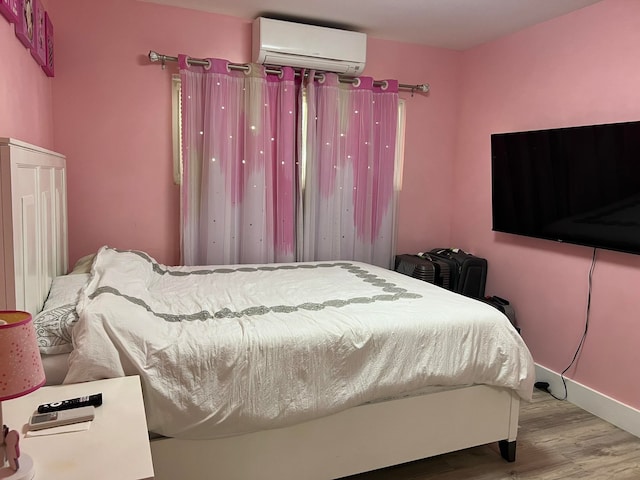 bedroom with a wall mounted air conditioner and wood-type flooring