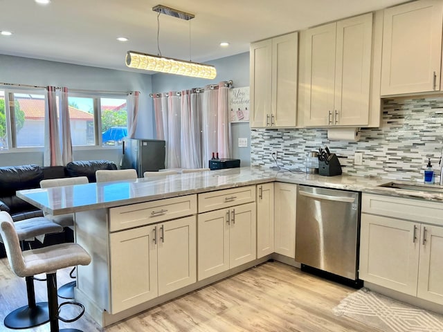 kitchen featuring dishwasher, hanging light fixtures, tasteful backsplash, light stone counters, and kitchen peninsula