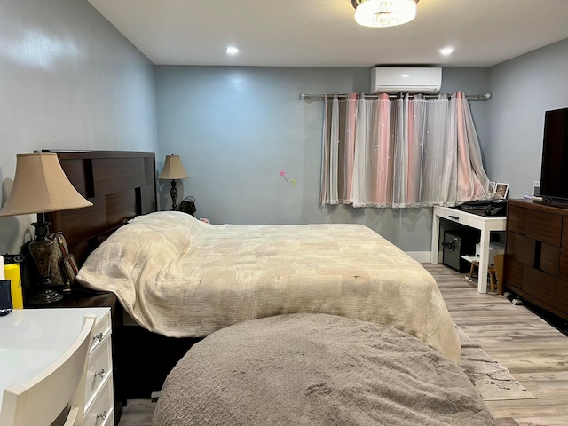 bedroom with light hardwood / wood-style flooring and a wall mounted AC