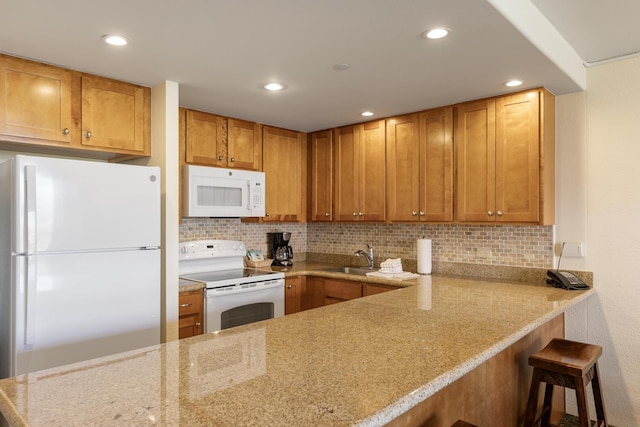 kitchen featuring white appliances, light stone countertops, recessed lighting, a sink, and decorative backsplash