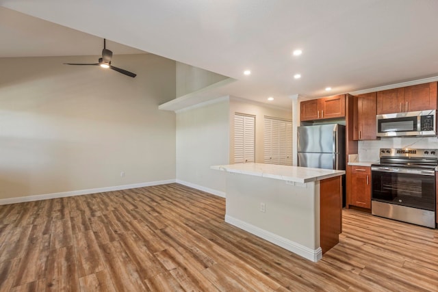 kitchen featuring light wood-type flooring, a center island, stainless steel appliances, and lofted ceiling