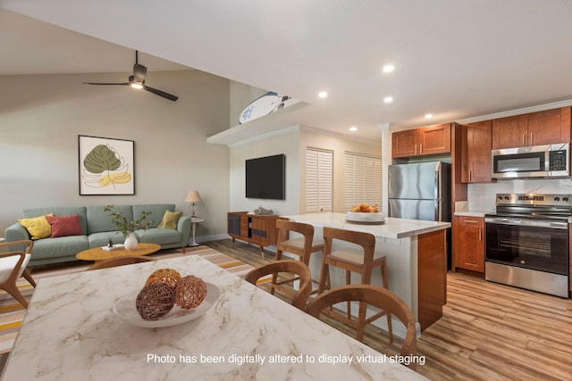 kitchen featuring light hardwood / wood-style flooring, vaulted ceiling, ceiling fan, ornamental molding, and stainless steel appliances