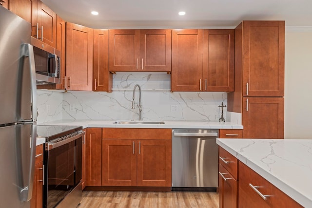 kitchen with sink, light hardwood / wood-style flooring, decorative backsplash, light stone counters, and stainless steel appliances