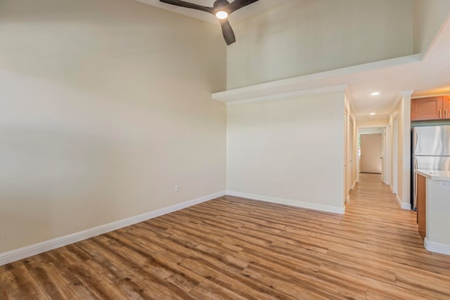 spare room with ceiling fan, a towering ceiling, and light hardwood / wood-style floors