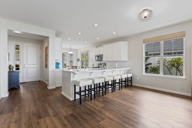 115 Nanu Pl, Wailuku, HI 96793 - kitchen with stainless steel appliances, a kitchen bar, a peninsula, dark wood-style flooring, and white cabinetry