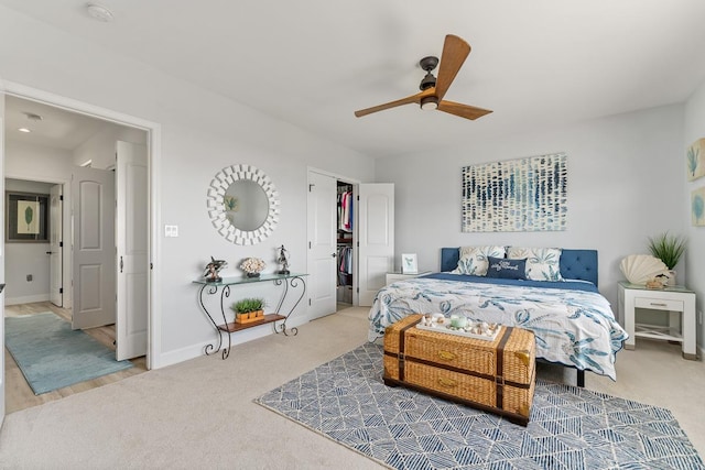 carpeted bedroom featuring baseboards, a ceiling fan, and a walk in closet