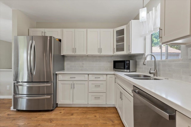 kitchen featuring backsplash, white cabinets, light wood-type flooring, and appliances with stainless steel finishes