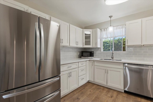 kitchen with stainless steel appliances, hardwood / wood-style flooring, white cabinetry, sink, and pendant lighting