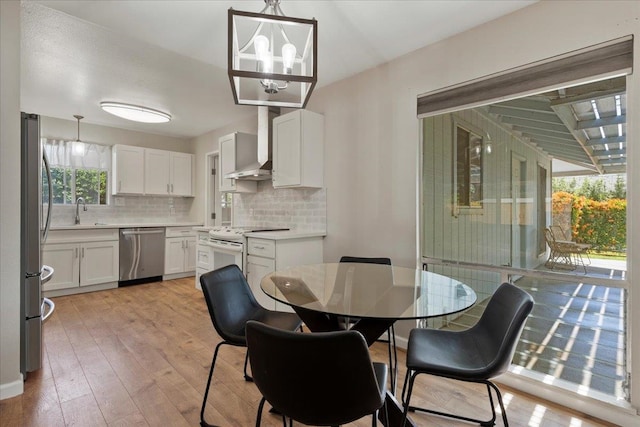 dining room featuring sink, light hardwood / wood-style flooring, and an inviting chandelier