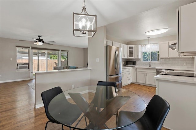 dining space with light hardwood / wood-style floors, sink, and ceiling fan with notable chandelier