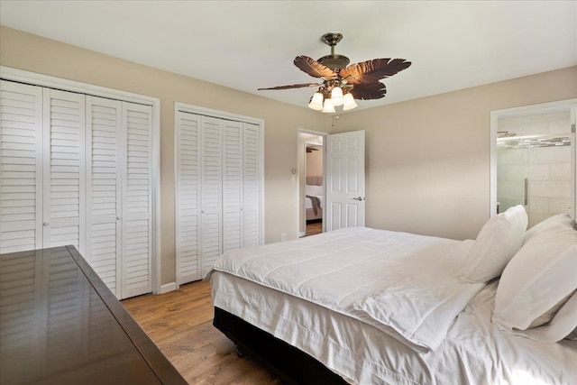 bedroom with multiple closets, hardwood / wood-style floors, connected bathroom, and ceiling fan