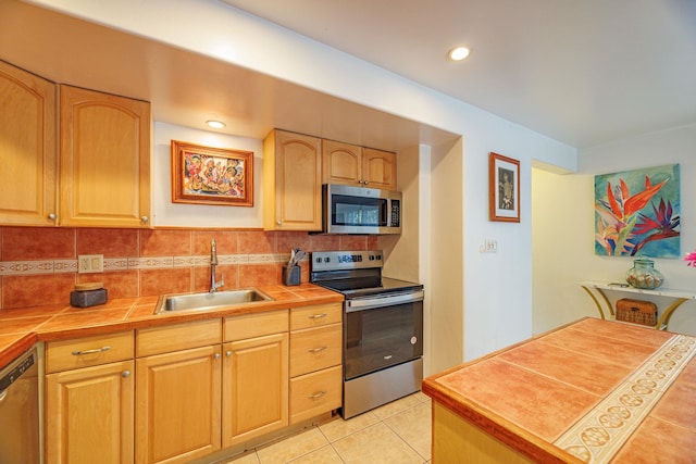 3559 Lower Honoapiilani Rd Unit 720, Lahaina, HI 96761 - kitchen featuring appliances with stainless steel finishes, a sink, tile counters, decorative backsplash, and light tile patterned flooring
