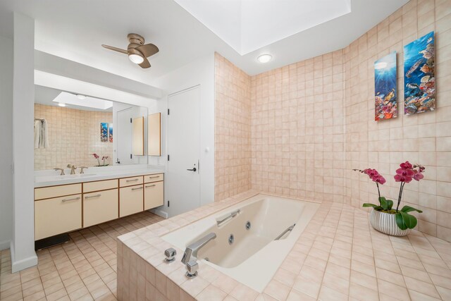 bathroom with tile walls, vanity, a relaxing tiled tub, and tile patterned floors