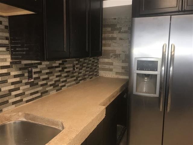 kitchen featuring tasteful backsplash and stainless steel refrigerator with ice dispenser