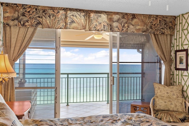 bedroom with light tile patterned flooring, a water view, and a textured ceiling