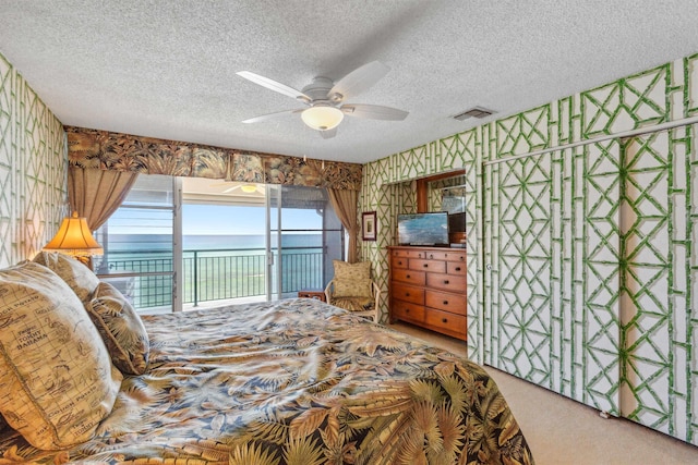 carpeted bedroom featuring access to outside, ceiling fan, and a textured ceiling