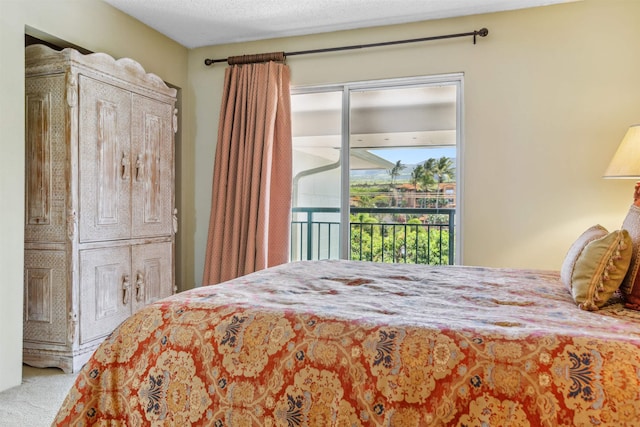 bedroom featuring access to exterior, carpet, and a textured ceiling