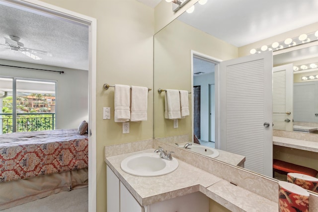 bathroom with ceiling fan, a textured ceiling, and vanity