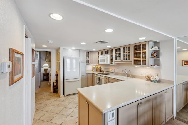 kitchen featuring kitchen peninsula, white appliances, sink, and light tile patterned floors