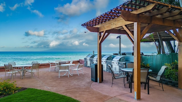 view of patio / terrace featuring a view of the beach, a pergola, a water view, and a grill