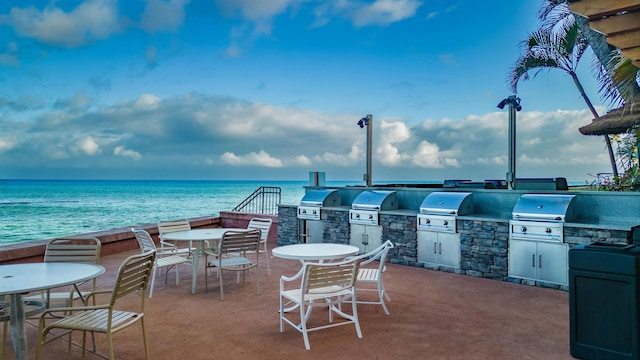 view of patio / terrace featuring grilling area, a water view, and exterior kitchen