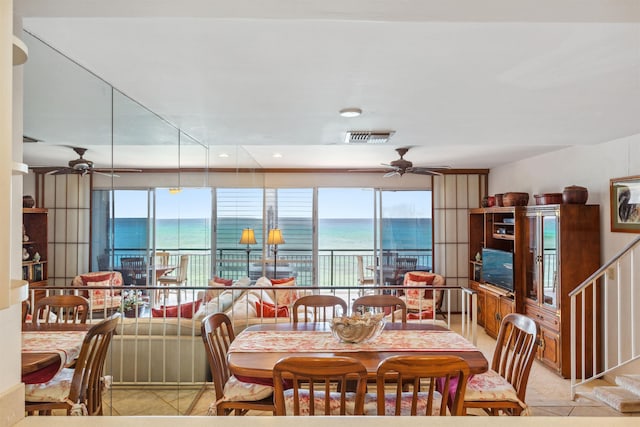 tiled dining area with a wealth of natural light, ceiling fan, and a water view