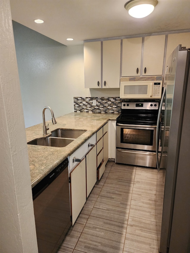 kitchen with stainless steel appliances, backsplash, sink, and white cabinetry