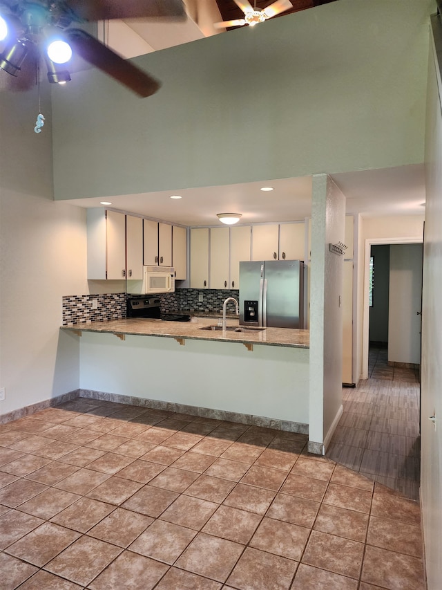 kitchen featuring stainless steel fridge with ice dispenser, white cabinetry, kitchen peninsula, a high ceiling, and ceiling fan