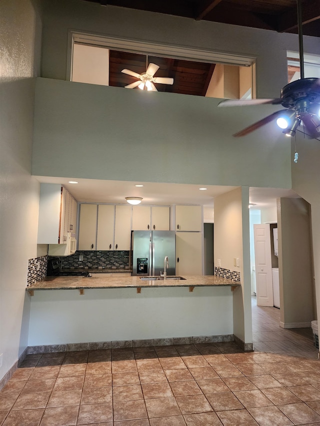 kitchen featuring white cabinetry, kitchen peninsula, a high ceiling, ceiling fan, and stainless steel fridge with ice dispenser