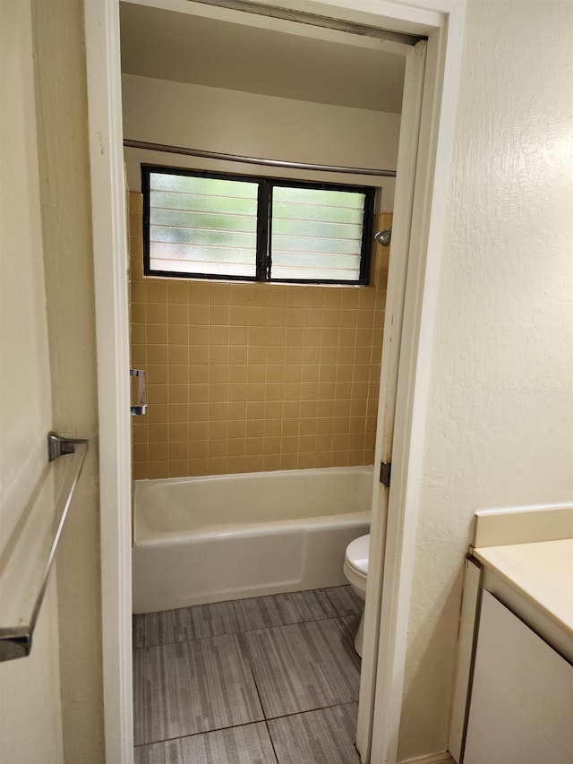 full bathroom featuring tiled shower / bath combo, vanity, and toilet