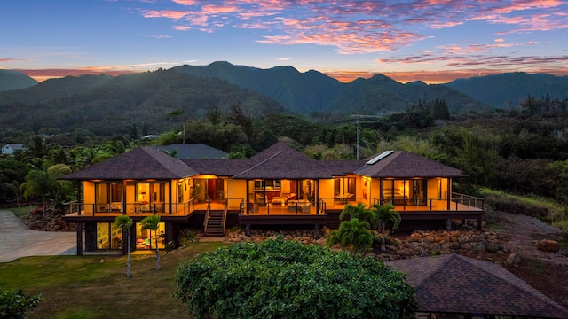 back house at dusk featuring a sunroom and a deck with mountain view