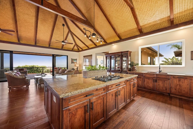 kitchen featuring light stone countertops, a center island, dark wood-type flooring, and stainless steel gas cooktop