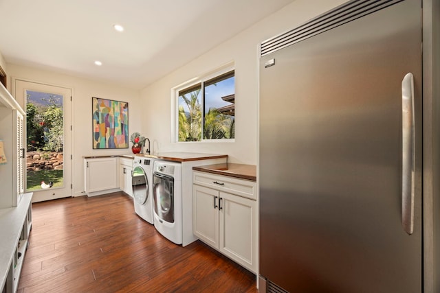 clothes washing area featuring cabinets, dark hardwood / wood-style flooring, and washer and dryer